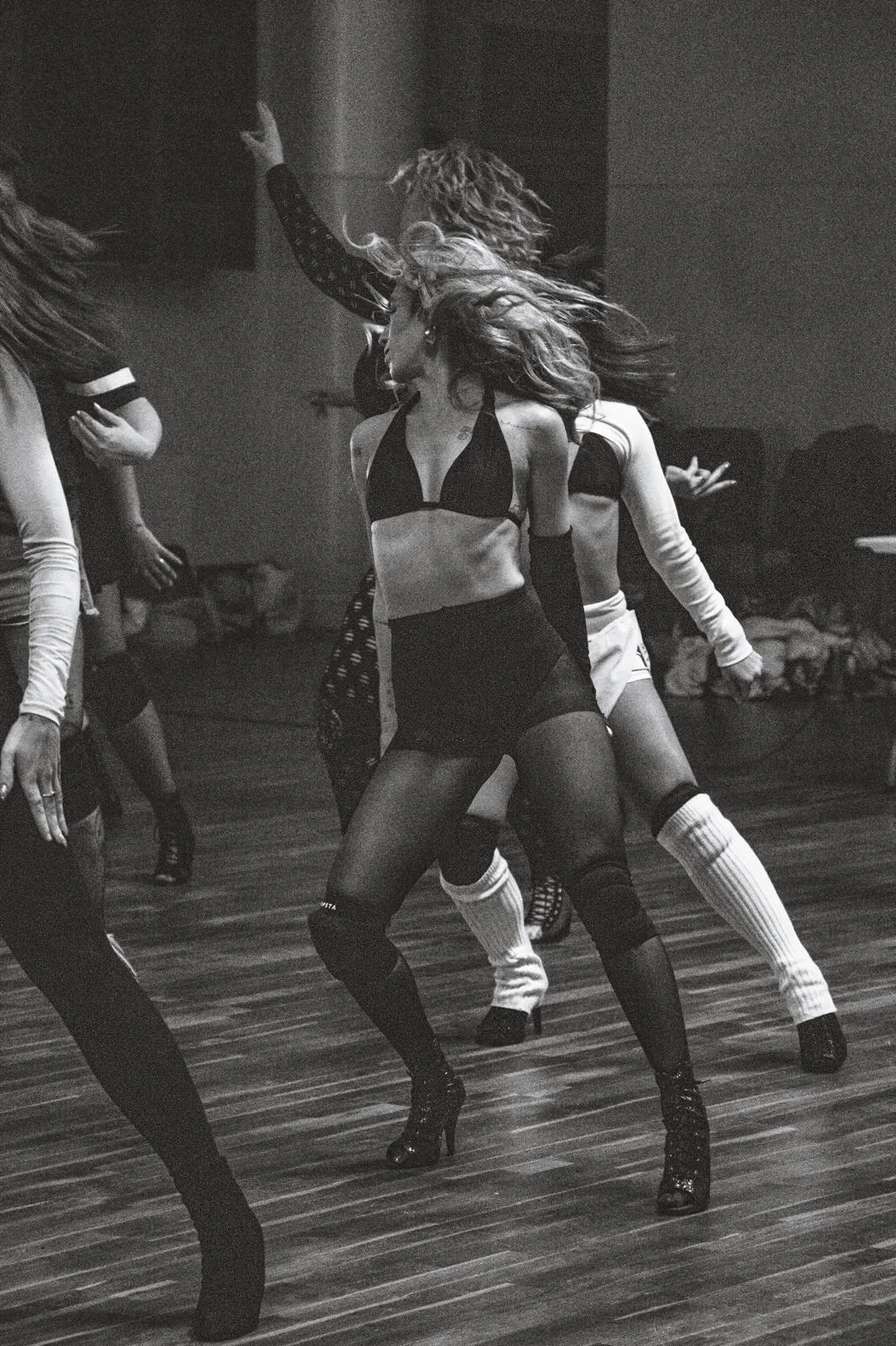 Dancer in heels mid hair-flip, shot in dramatic black and white studio light